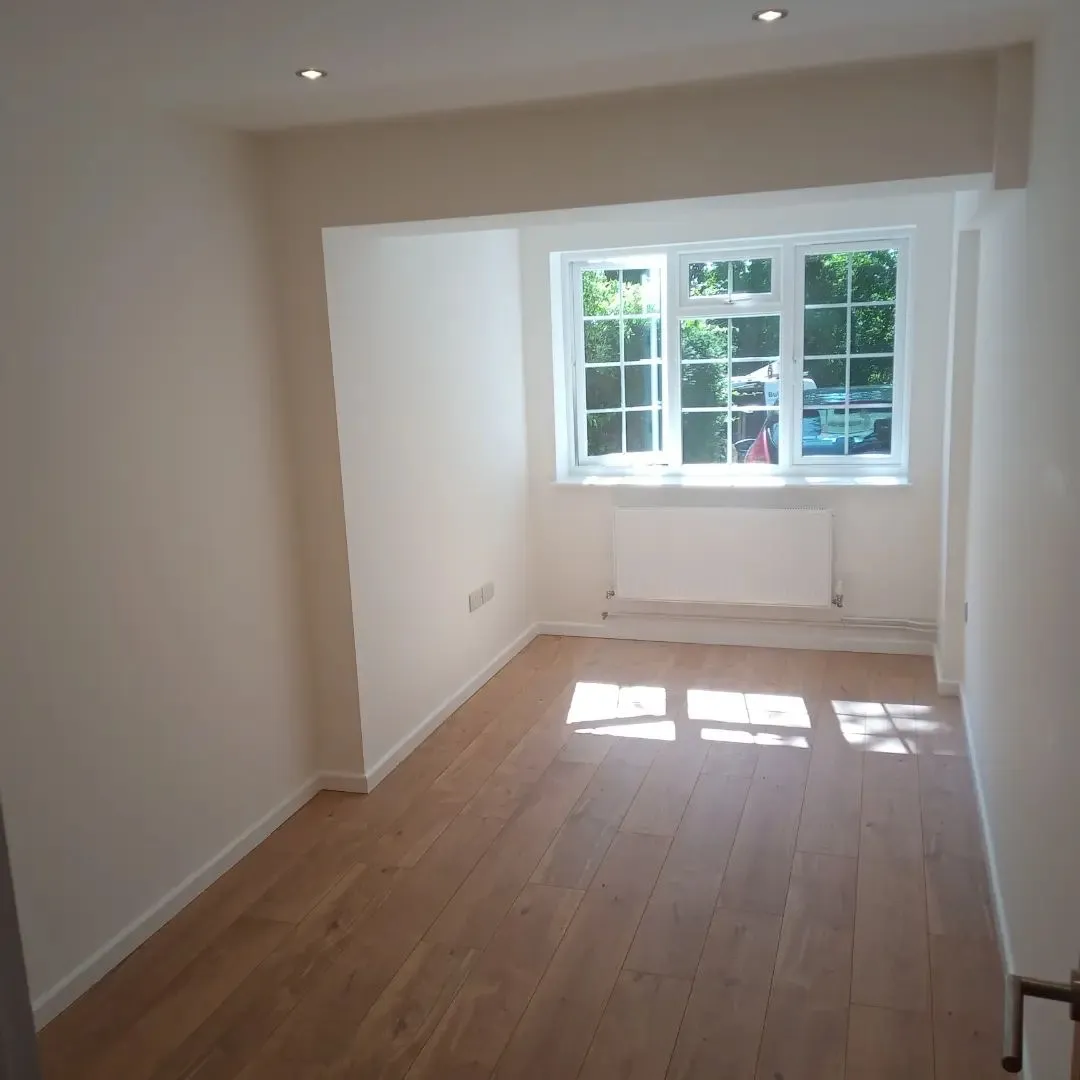 A garage conversion with a window and a hard wood floor.