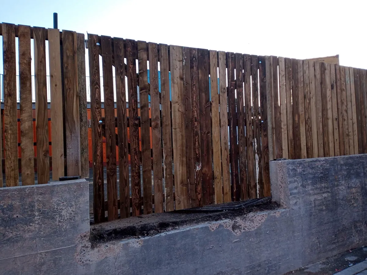 a fence made of wooden slats on the side of a road